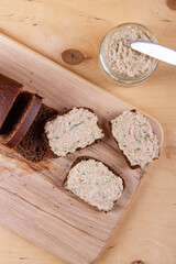 Homemade bread on wooden cutting board with spread and greens