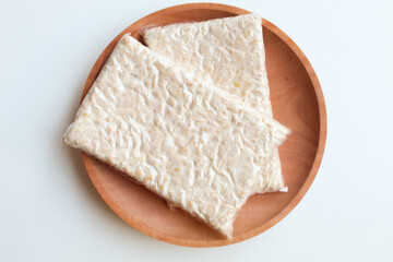 Tempeh or tempe, processed soy product, on wooden background. Isolated on white background. Flat...