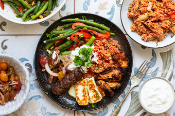 Middle eastern plate with couscous, lamb kofta, green bean salad and halloumi