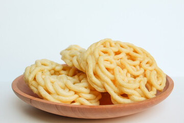 Kerupuk Mie Kuning or Yellow Noodles Crackers, food condiment from Indonesia. On wooden plate. Isolated on white background