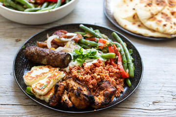 Middle eastern plate with couscous, lamb kofta, green bean salad and halloumi