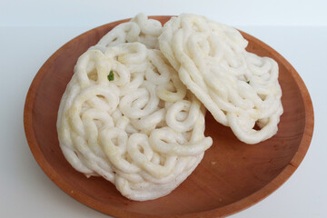 Kerupuk Mie or Noodles Crackers, food condiment from Indonesia. On wooden plate. Isolated on white background