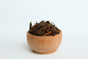 Fototapeta na wymiar Dried black tea before brew, in a wooden bowl. Isolated on white background