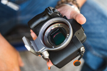 Close up of man hand hold digital camera full frame sensor and lens mount.