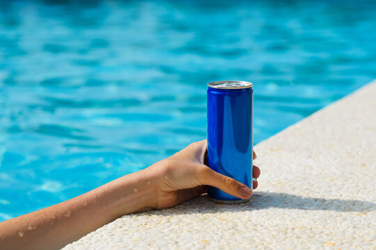 Hand with a can of cold drink by the pool. Summer vacation. Good service concept. Close-up