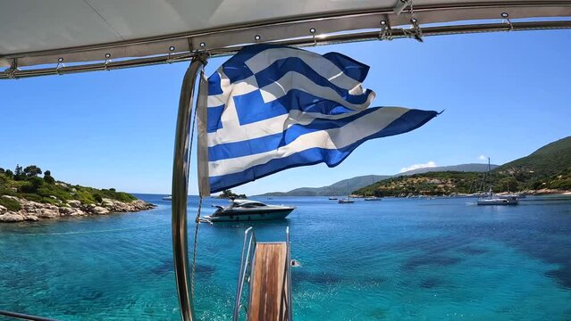 Greek flag on boat cruise around the island of Ithaki or Ithaca in the Ionian sea in the Mediterranean sea of Greece