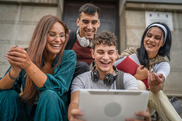 group of students sit in front of school watch video on digital tablet