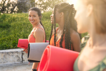 Three young women in sportswear walking together outside after yoga class
