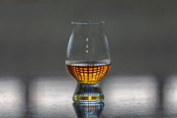 Single malt scotch whiskey in glencairn tasting glass with window reflection in liquid