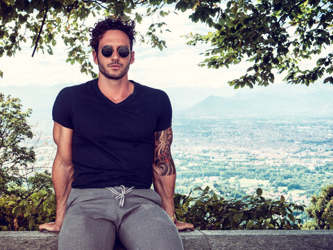 Photo of a man perched on a stone wall, enjoying the view