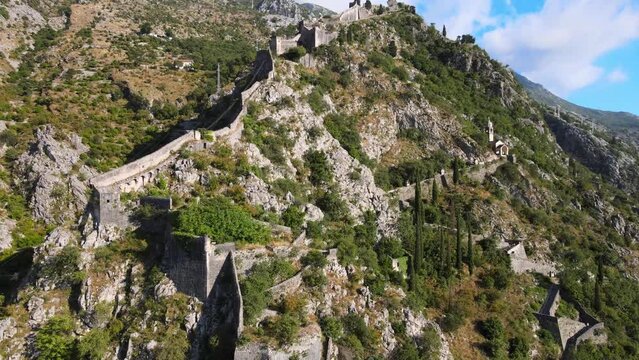 A camera drone flies toward the ancient walls of Kotor Old Town, Montenegro