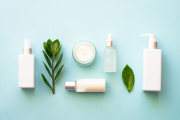 Natural cosmetic products. Cream, serum, tonic with green leaves. Top view on blue background.