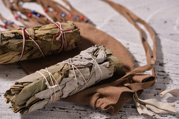 Close up of two smudge sticks with white sage, yerba santa and eucalyptus leavers on a medicinal...