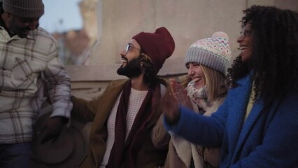Happy group friends enjoying meeting evening winter outdoor. Cheerful young multiracial colleagues have fun together on holiday. Millennial people greeting each other joyful at their Christmas reunion