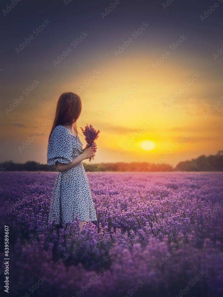 Wall mural side portrait of a young woman in dress stands in the purple lavender field looking at the beautiful