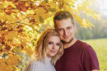 Young loving couple is posing in the autumn park. Horizontally. 