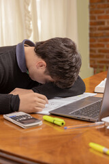 Frustrated student boy, studying in front of a laptop.