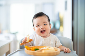 離乳食後期でをつかみ食べをしてご機嫌な生後9か月の赤ちゃん