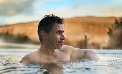 Man relaxing in hot water pool outdoor in autumn