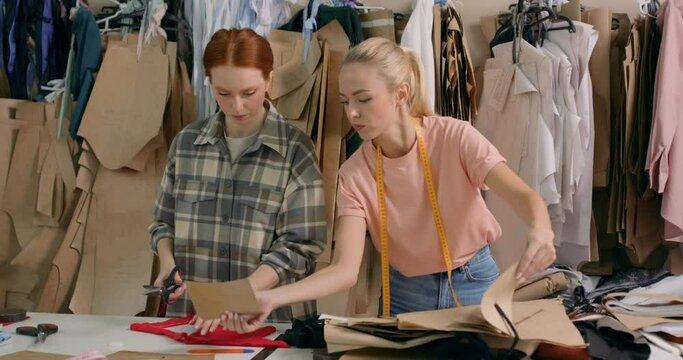 two active tailors fashion designers doing some work in textile factory, choosing fabric, patten and having talk. ladies workers getting some garments ready for embroidery in textile factory team work