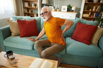 Unhappy senior man suffering from backache at home