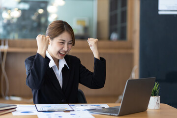 Attractive Asian businesswoman in the office working with financial documents on the desk.