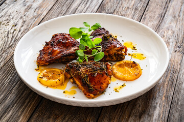 Roasted chicken thighs with lemon on wooden table
