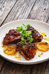 Roasted chicken thighs with lemon on wooden table

