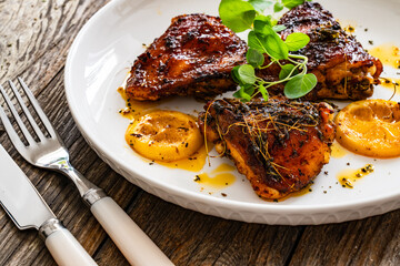 Roasted chicken thighs with lemon on wooden table
