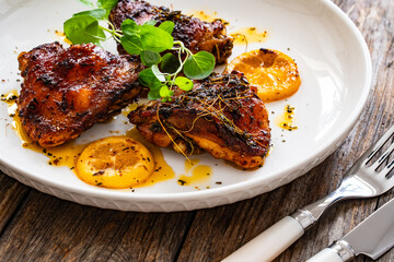 Roasted chicken thighs with lemon on wooden table
