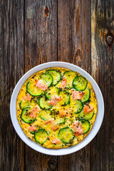Omelette - scrambled eggs with smoked salmon and zucchini on wooden table