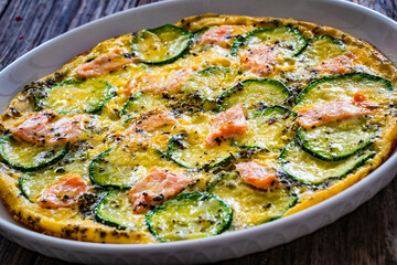 Omelette - scrambled eggs with smoked salmon and zucchini on wooden table