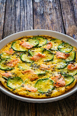 Omelette - scrambled eggs with smoked salmon and zucchini on wooden table