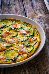 Omelette - scrambled eggs with smoked salmon and zucchini on wooden table