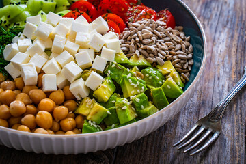 Fresh vegetable salad with feta cheese on wooden table
