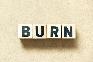 Alphabet letter block in word burn on wood background