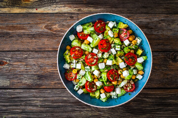 Fresh vegetable salad with feta cheese on wooden table
