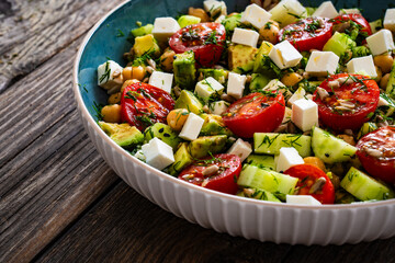 Fresh vegetable salad with feta cheese on wooden table
