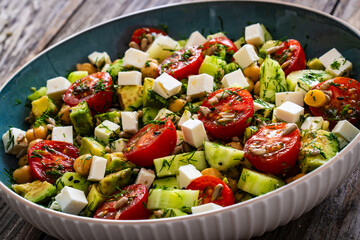Fresh vegetable salad with feta cheese on wooden table
