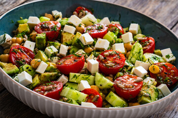 Fresh vegetable salad with feta cheese on wooden table
