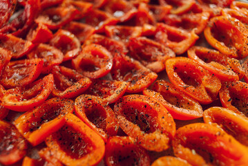 Sun-dried tomatoes on a baking tray. Fresh tomatoes sprinkled with aromatic seasonings
