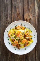 Tagliatelle with chanterelle mushrooms, seared prawns and   Parmigiano Reggiano on wooden table
