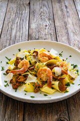 Tagliatelle with chanterelle mushrooms, seared prawns and   Parmigiano Reggiano on wooden table
