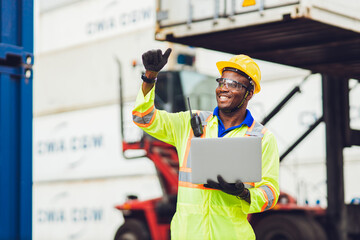 African male dock worker control loading containers cargo at warehouse container shipyard. Marine...