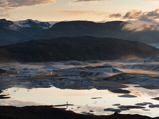 Mensch in grandioser Landschaft mit Gletschersee schaut ins Abendlicht