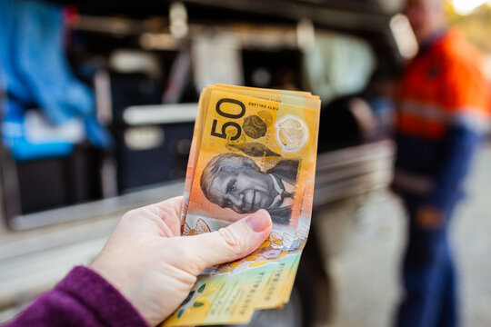 Close up of cash payment in woman's hand to pay tradesman for job