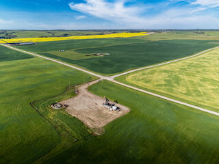 Aerial oil and gas well at crossroads overlooking agriculture fields on the Canadian prairies in Alberta Canada.