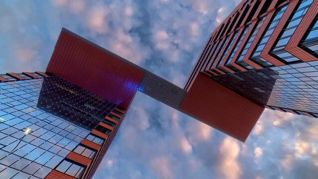 Day to night timelapse of modern glass building (business center with offices) against cloudy dramatic sky.