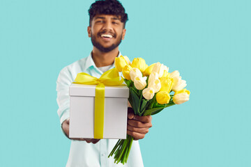Gift with flowers for girlfriend or close friend in hands of Indian man holding out bouquet of...