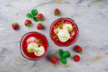 Traditionelle gefrorene Erdbeersuppe mit Vanilleeis und gehackte Pistazien serviert als Draufsicht auf einem Design Board mit Textfreiraum